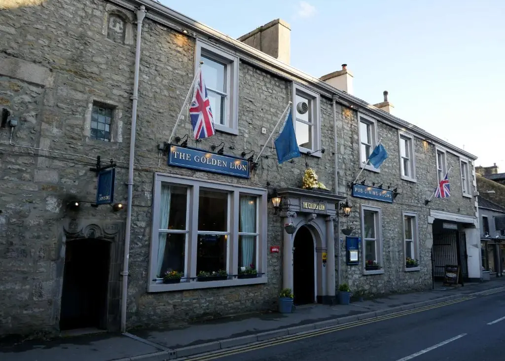 A terrace building with a sign on the wall that reads 'The Golden Lion'. There's 2 union jacks on the wall.