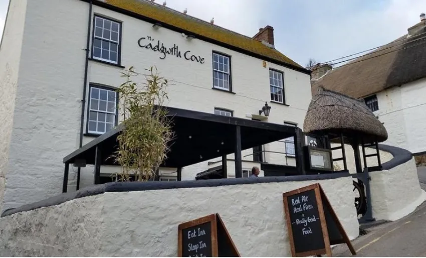 A pretty white building with 'The Cadgwith Cove' written on the wall in an elegant font. 