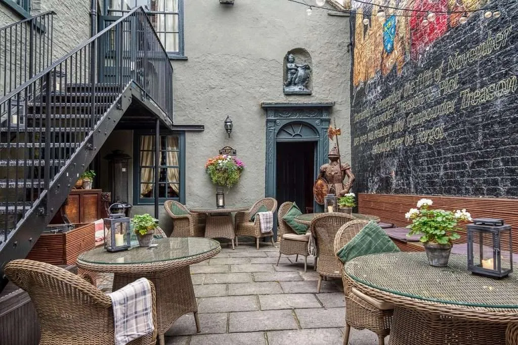Guy Fawkes Pub garden, York. Tables, chairs, decorative wall, flowers, and steps on the left.